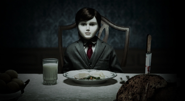 Os 13 bonecos amaldiçoados mais macabros do cinema e da internet Foto do Boneco do Mal. Ele é pálido, veste um terno e está sentado na mesa de jantar