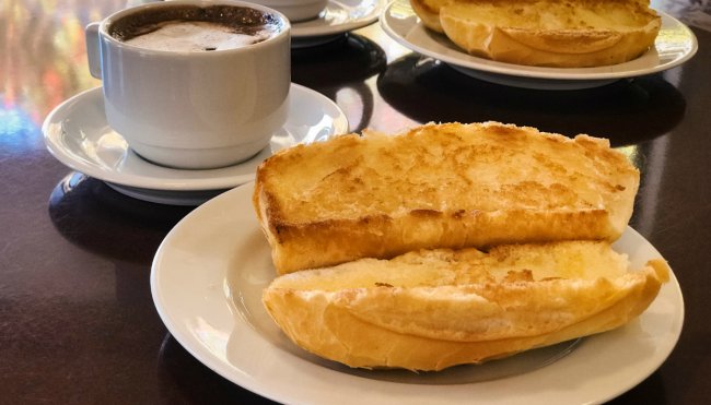 23 provas de que pão é uma das coisas mais maravilhosas que existem Foto de um pão na chapa ao lado de uma xícara de café