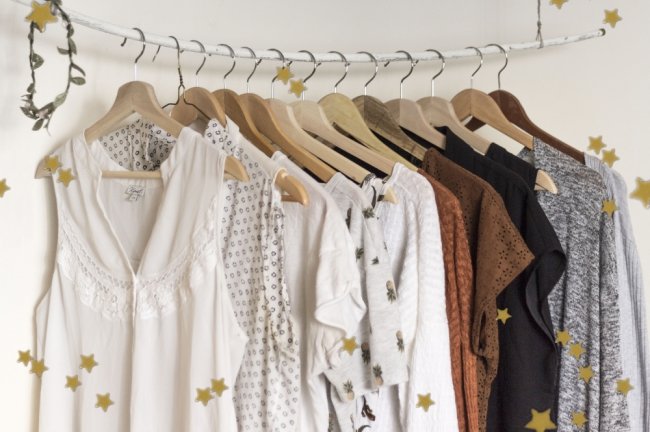 ideias minimalismo Roupas penduradas em arara branca. As peças são dos tons cinza, bege, branco.