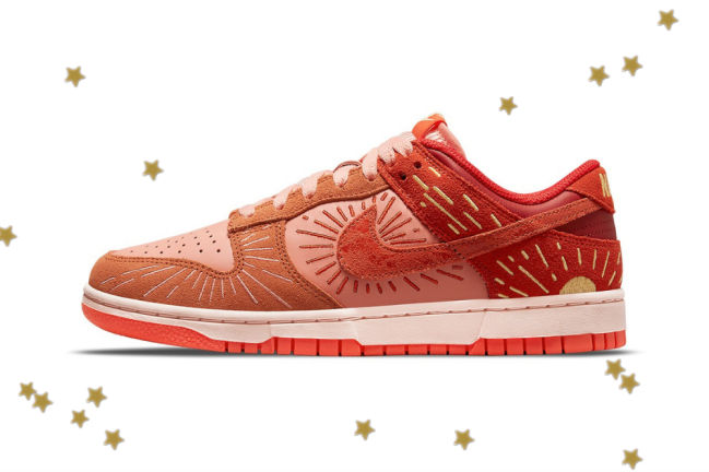 novo dunk low Foto com fundo branco e com estrelinhas douradas. No centro, temos o novo tênis da Nike do modelo Dunk Low com as cores laranja, vermelho e detalhes em amarelo.