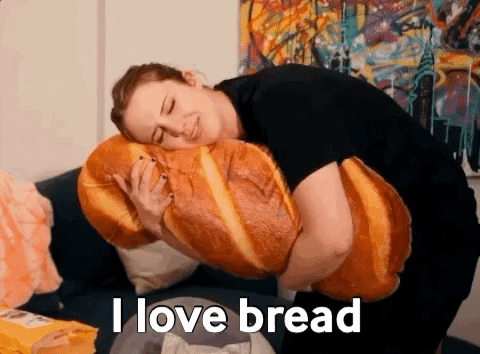 23 provas de que pão é uma das coisas mais maravilhosas que existem Gif de uma mulher segurando uma almofada gigante de pão e dizendo que ama muito o alimento