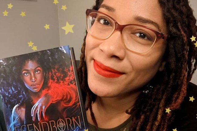 tracy deonn lendarios Selfie de Tracy Deonn, autora do livro Lendários, segurando a versão da obra em inglês; ela sorri levemente e está usando óculos e batom vermelho; estrelas amarelas decoram a imagem