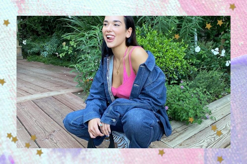 Dua Lipa sorridente posando sentada e com look all jeans.