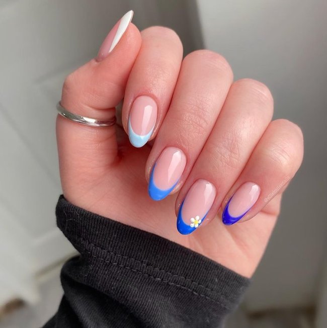 francesinha-sorriso-tons-de-azul Foto de uma mão com anel no polegar. As unhas estão com francesinhas em diferentes tons de azul.