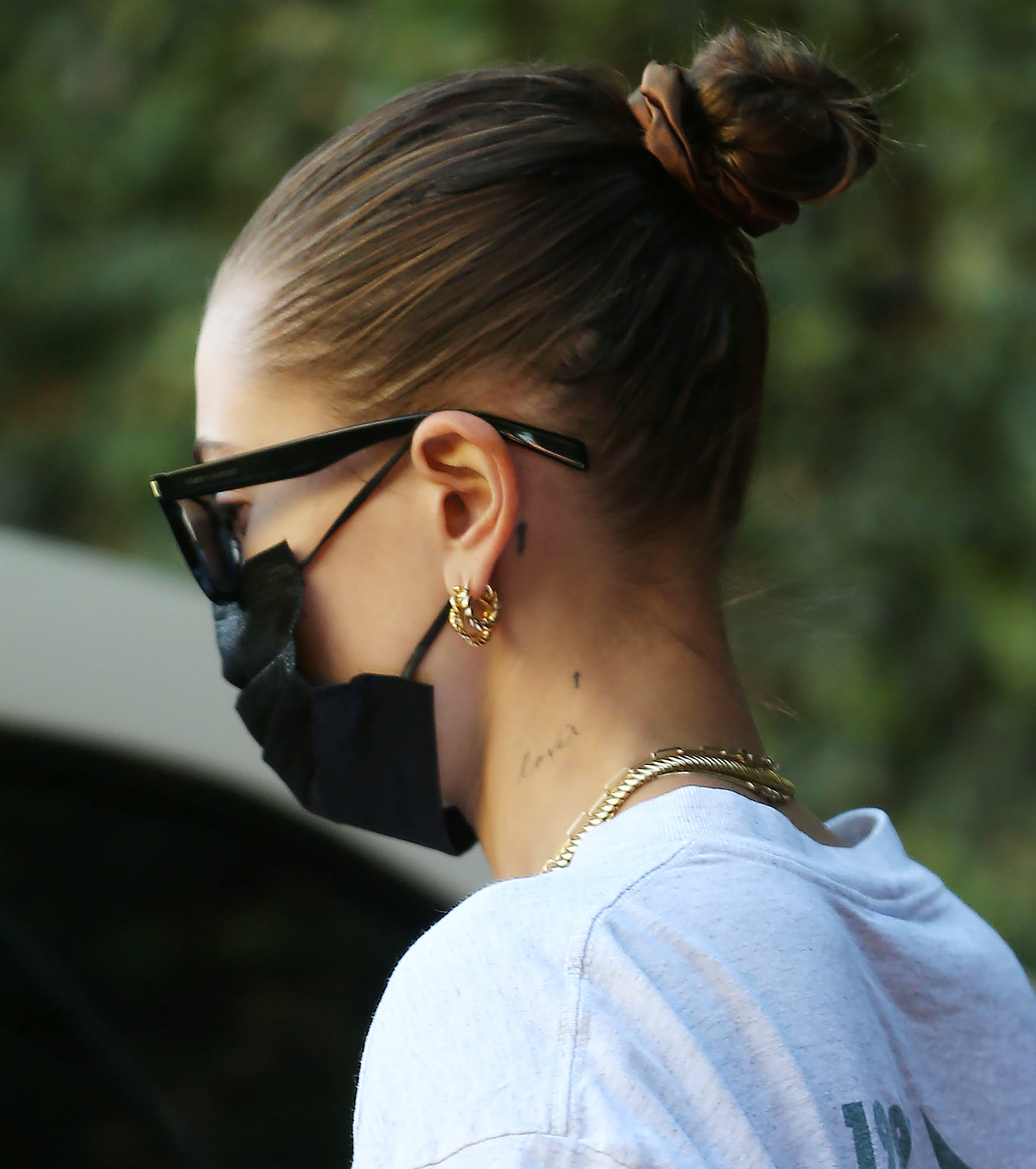 Celebrity Sightings In Los Angeles – October 29 2021 Foto da Hailey Bieber de costas com cabelo preso num coque com scrunchie, usando óculos escuros e máscara facial preta
