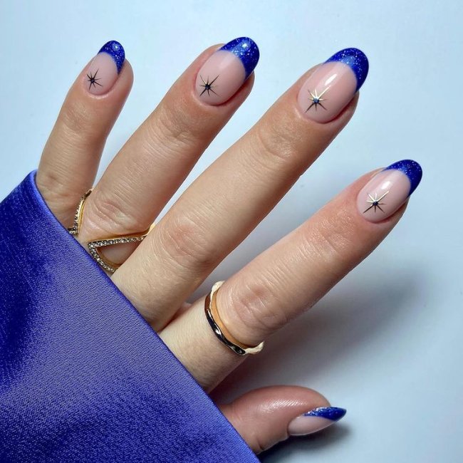nail-art-com-brilhos Foto de uma mão com nail art de francesinha azul com brilhos.