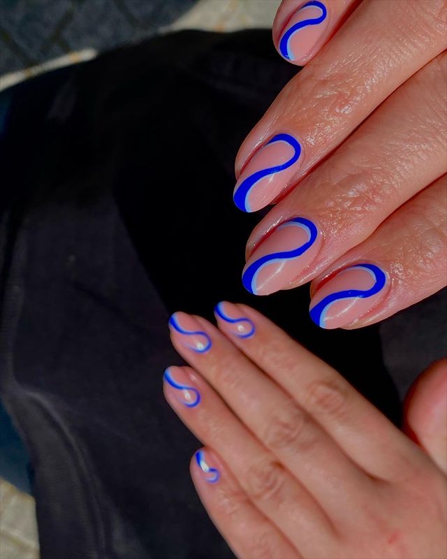 nail-art-com-ondas-azuis Foto de unhas da mão com decoração minimalista com ondas em tons de azul.