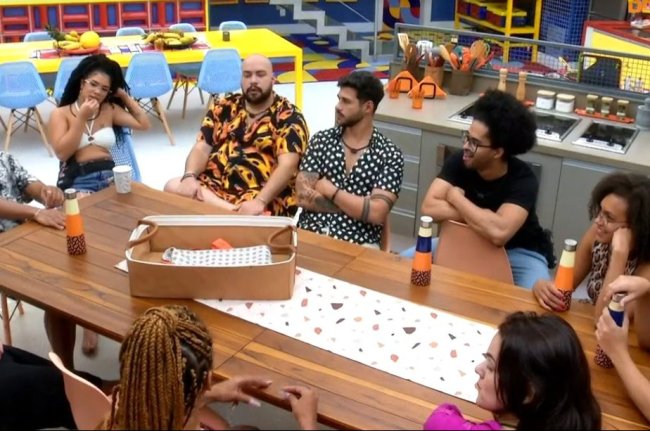 BBB22-Capricho Print da imagem da câmera do Big Brother Brasil. As pessoas estão reunidas, sentadas na mesa do cozinha.