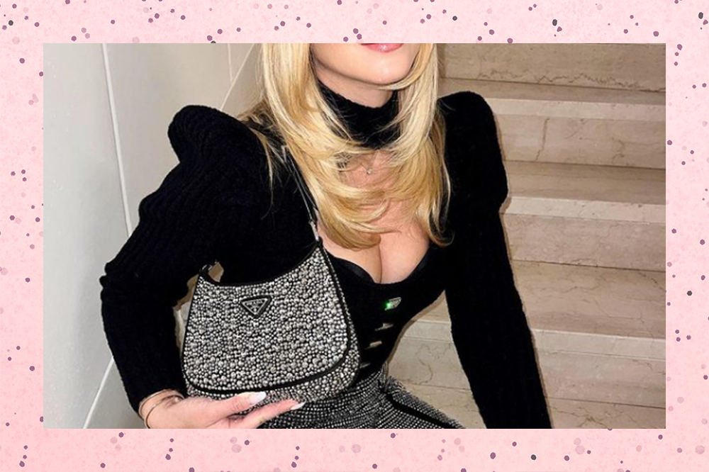 Garota usando bolsa da Prada de brilhos e blusa preta em montagem com fundo rosa de bolinhas. Na foto, dá para ver o cabelo loiro da influenciadora Valentina Ferragni e sua mão segurando a bolsa.