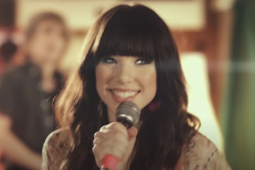 Imagem de Carly Rae Jepsen sorrindo e segurando o microfone no clipe de Call Me Maybe