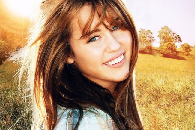 hannah-montana Miley sorrindo em um campo e cabelos ao vento.