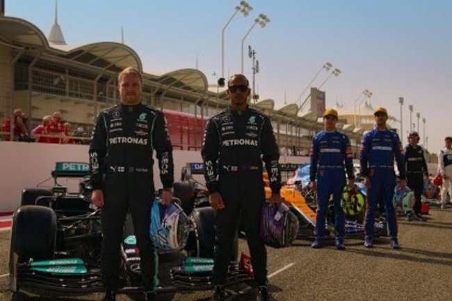 f1-dirigir-para-viver Pilotos frente aos carros em uma pista de corrida.