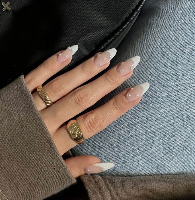 francesinha-sorriso-com-perolas Foto de uma mão com as unhas longas decoradas com uma francesinha branca clássica e aplicação de pérolas.