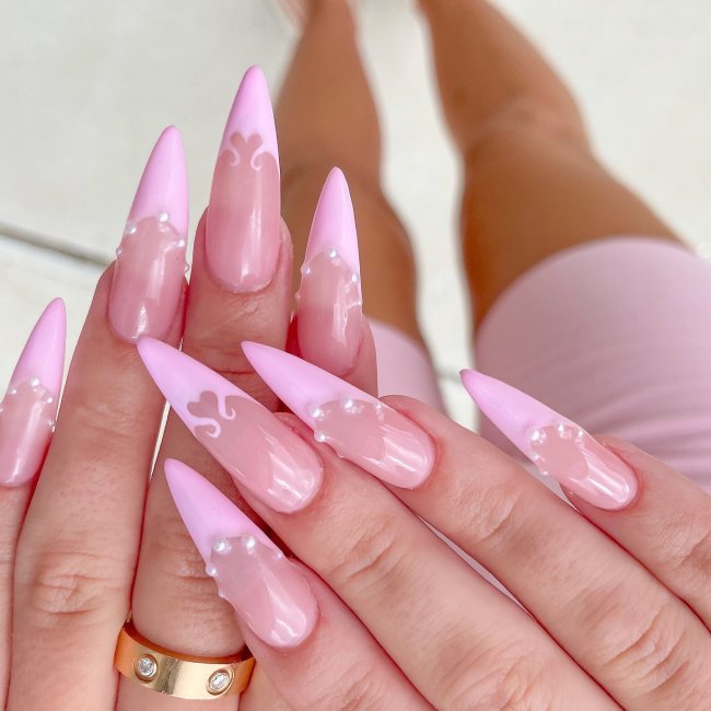 nail-art-rosa-com-perolas Foto de mãos com as unhas longas decoradas com uma francesinha rosa e aplicação de pérolas.
