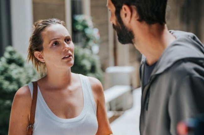 naquele-fim-de-semana Uma mulher de regata branca e bolsa conversando com um homem de costas.