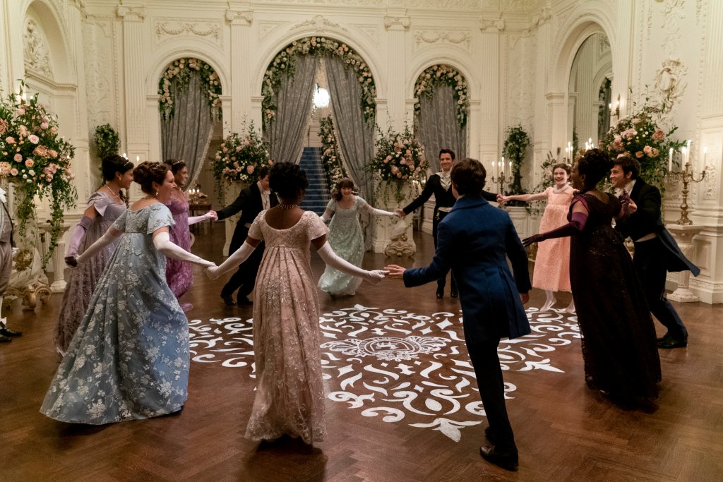 Imagem mostra, da esquerda para a direita, Shelley Conn como Mary Sharma, Ruth Gemmell como Lady Violet Bridgerton, Simone Ashley como Kate Sharma, Luke Newton como Colin Bridgerton, Charithra Chandran como Edwina Sharma, Claudia Jessie como Eloise Bridgerton, Luke Thompson como Benedict Bridgerton, Will Tilston como Gregory Bridgerton, Florence Emilia Hunt como Hyacinth Bridgerton, Adjoa Andoh como Lady Danbury, Jonathan Bailey como Anthony Bridgerton dançando juntos em cena da 2ª temporada de Bridgerton.