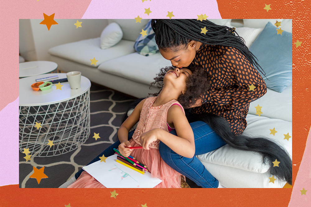 Imagem mostra mãe e filha sentadas no sofá e no chão, respectivamente. Ambas então em uma sala de estar enquanto a mãe trança o cabelo da filha e a mesma olha para cima e recebe um beijo na testa. O registro de trocas e afetos entre mãe e filha segue acompanhado de uma borda colorida e estrelinhas douradas por toda a imagem.