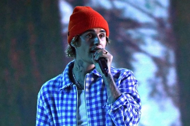 justin-bieber Justin Bieber cantando no palco com touca laranja.
