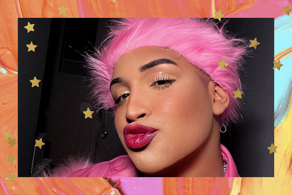 Selfie de Yarley com look na cor rosa; a margem é uma textura de tinta nas cores laranja, azul, amarelo e verde com estrelas amarelas como decoração