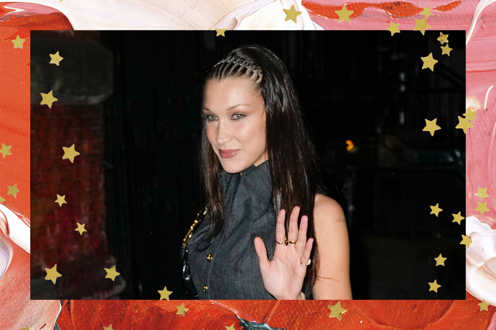 Imagem mostra Bella Hadid usando conjuntinho cinza, tiara de mola em zigue-zague, enquando acena para os fãs em chegada à festa de 27 anos de Gigi Hadid no Zero Bond em 23 de abril de 2022 na cidade de Nova York.