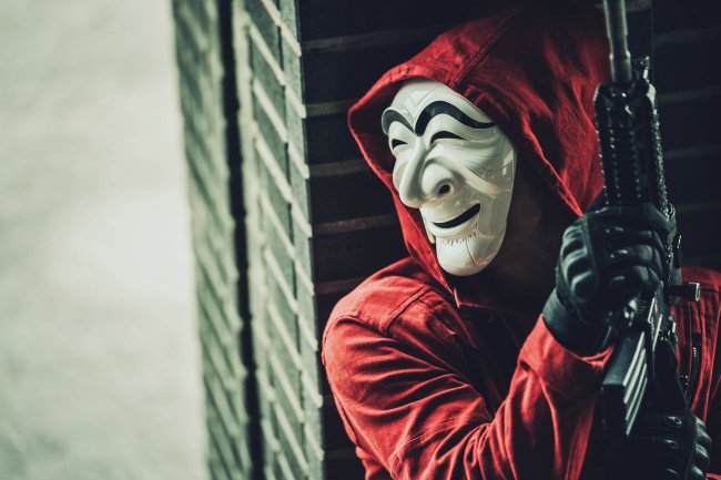 Máscara – La casa de papel coreia – Netlfix Personagem de La Casa de Papel Coreia olhando pela janela usando macacão vermelho com capuz e máscara