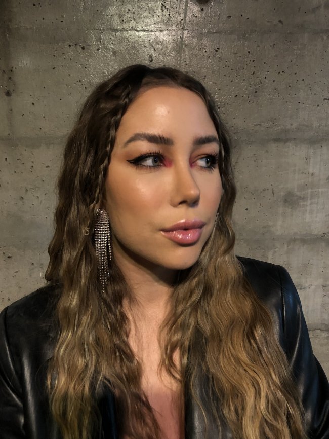 trancinhas-na-frana Foto close no rosto da Dayana Langaro na São Paulo Fashion Week nº53. Ela está com o cabelo solto e duas tranças na franja e maquiagem com detalhe rosa. Ela está de perfil e não sorri para a foto.