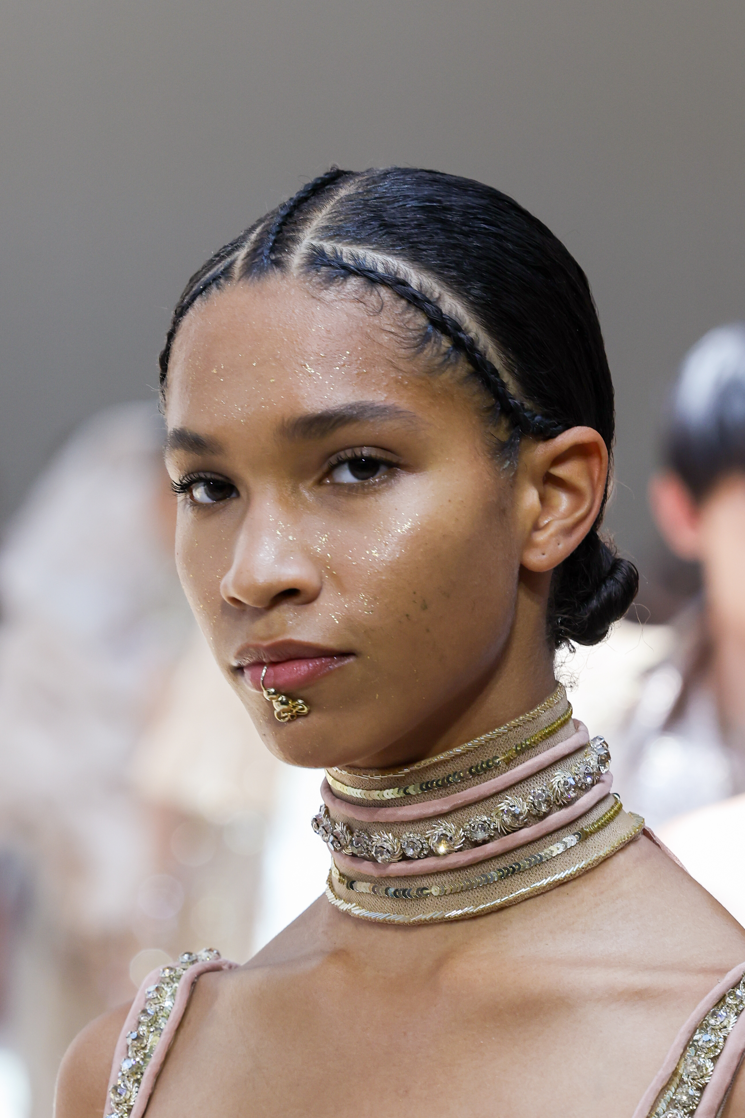 Elie Saab : Runway – Paris Fashion Week – Haute Couture Fall Winter 2022 2023 Modelo com penteado com trança de raiz e space buns baixo e glitter no rosto no Desfile de outono-inverno 2022-23 da Elie Saab na semana de alta-costura em Paris