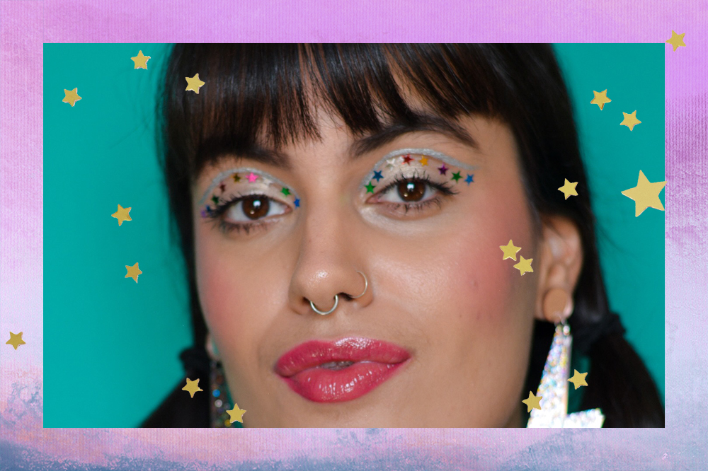 Montagem em fundo degradê lilás e azul com estrelinhas douradas de menina com franja usando maquiagem com delineador prata no côncavo e estrelinhas coloridas coladas nos olhos