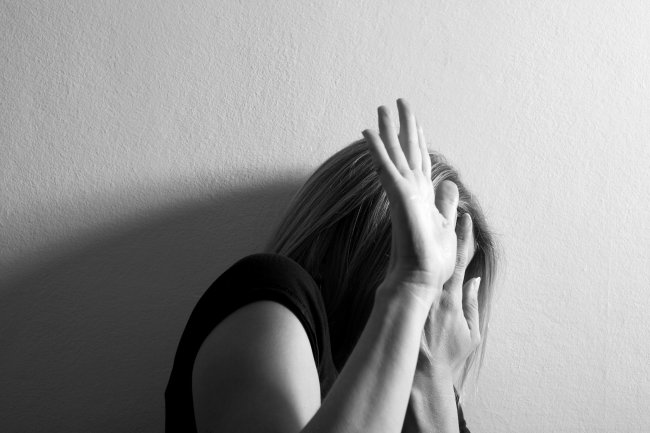 O governo atual propôs 94% menos de recursos Orçamento para combate à violência contra mulheres Fotografia de uma mulher se protegendo com as mãos