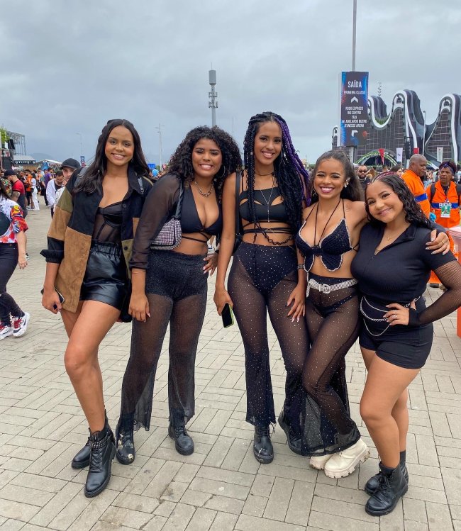 looks-all-black-rock-in-rio-2022 Foto de cinco meninas com look all black no Rock in Rio 2022. Todas elas olham para a câmera e sorriem para a foto.