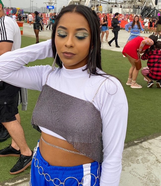 maquiagem-aplicacao-de-strass-rock-in-rio-2022 Foto da maquiagem de uma menina no Rock in Rio 2022. Ela está com sombra azul com aplicação de strass nos olhos. Ela olha para baixo e não sorri.