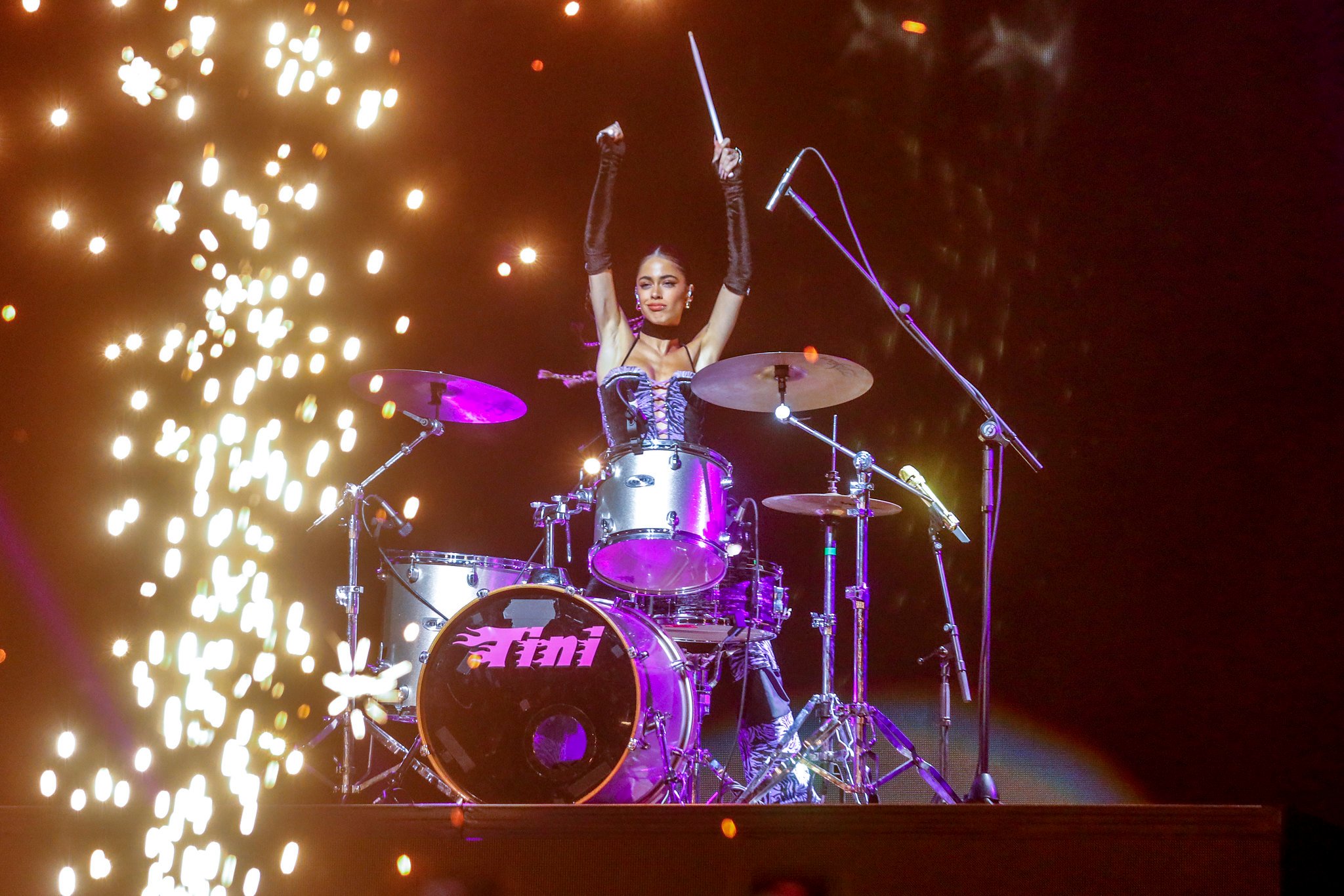 TINI tocando em uma bateria no palco