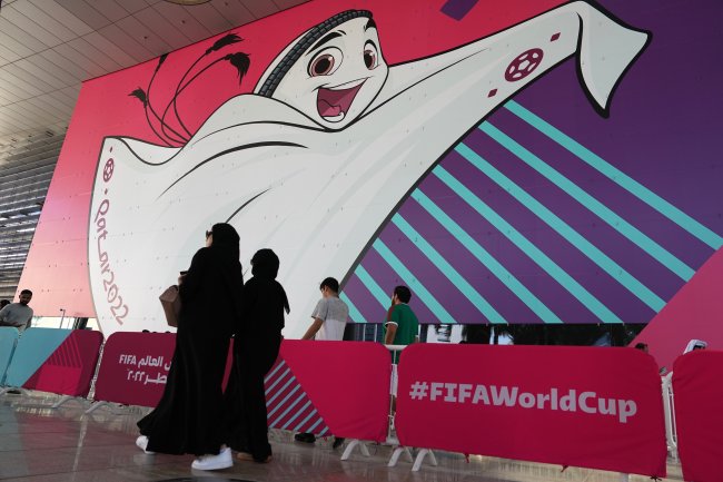 9 curiosidades e polêmicas sobre a Copa do Mundo 2022, no Catar Mulheres islâmicas usando hijab passeiam em frente a um cartaz com o mascote da Copa do Mundo 2022