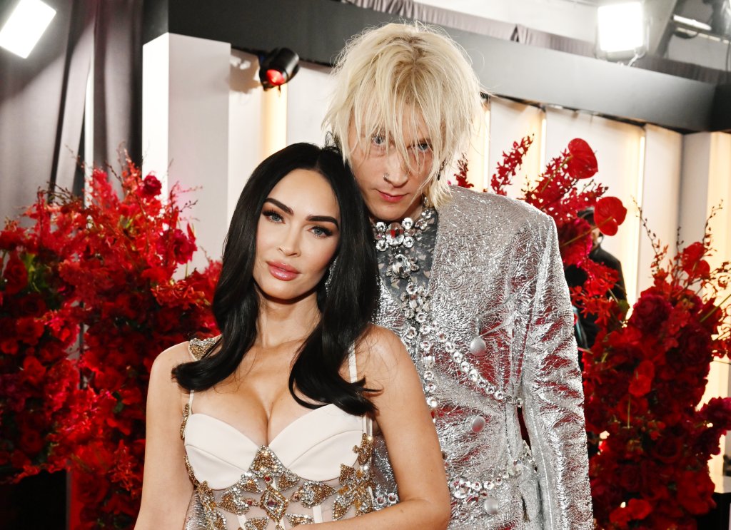 Megan Fox e Machine Gun Kelly posando para foto juntos com expressões neutras