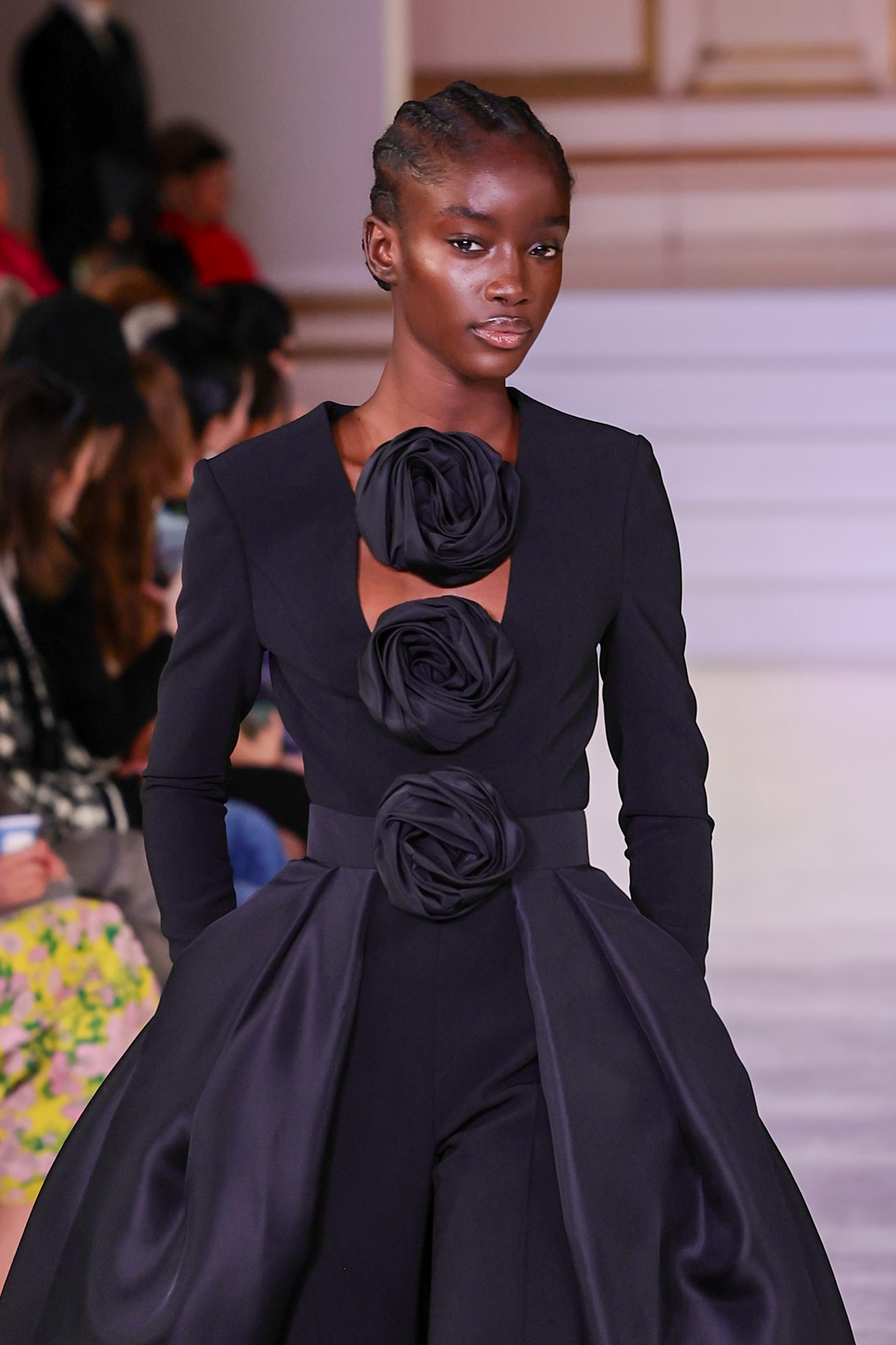 Desfile da Carolina Herrera na semana de moda de Nova York em fevereiro de 2023. Modelo usando vestido preto com detalhes de flores em 3D