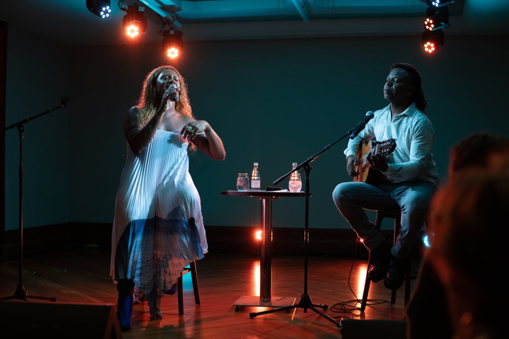 Cantora ajeita roupa ao lado de violinista