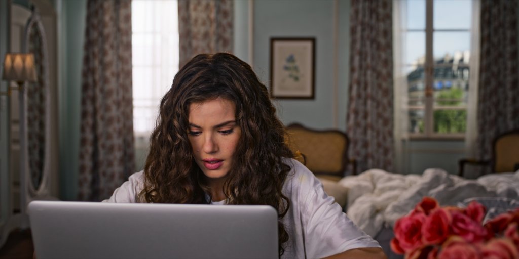 Camila Queiroz como Anita em De Volta aos 15; ela está digitando em um notebook