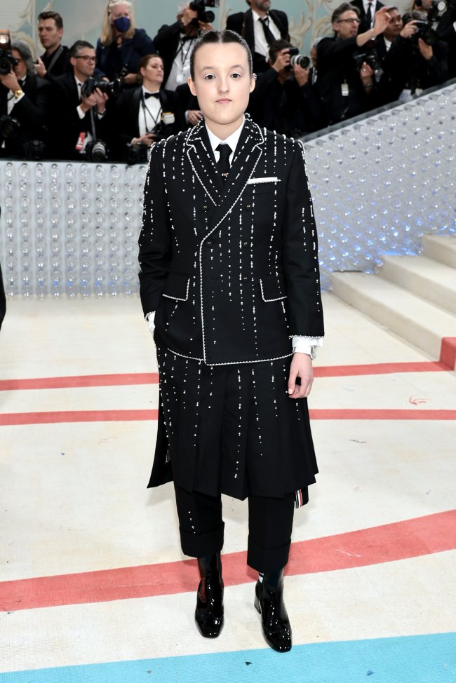 Bella Ramsey usa conjunto de terno e saia da marca Thom Browne no MET Gala Pessoa usa terno e saia no MET Gala