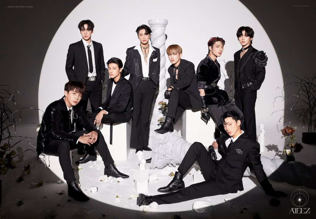 Imagem dos integrantes do grupo ATEEZ posando para foto em um fundo branco iluminado por uma luz de holofote redonda no centro da imagem