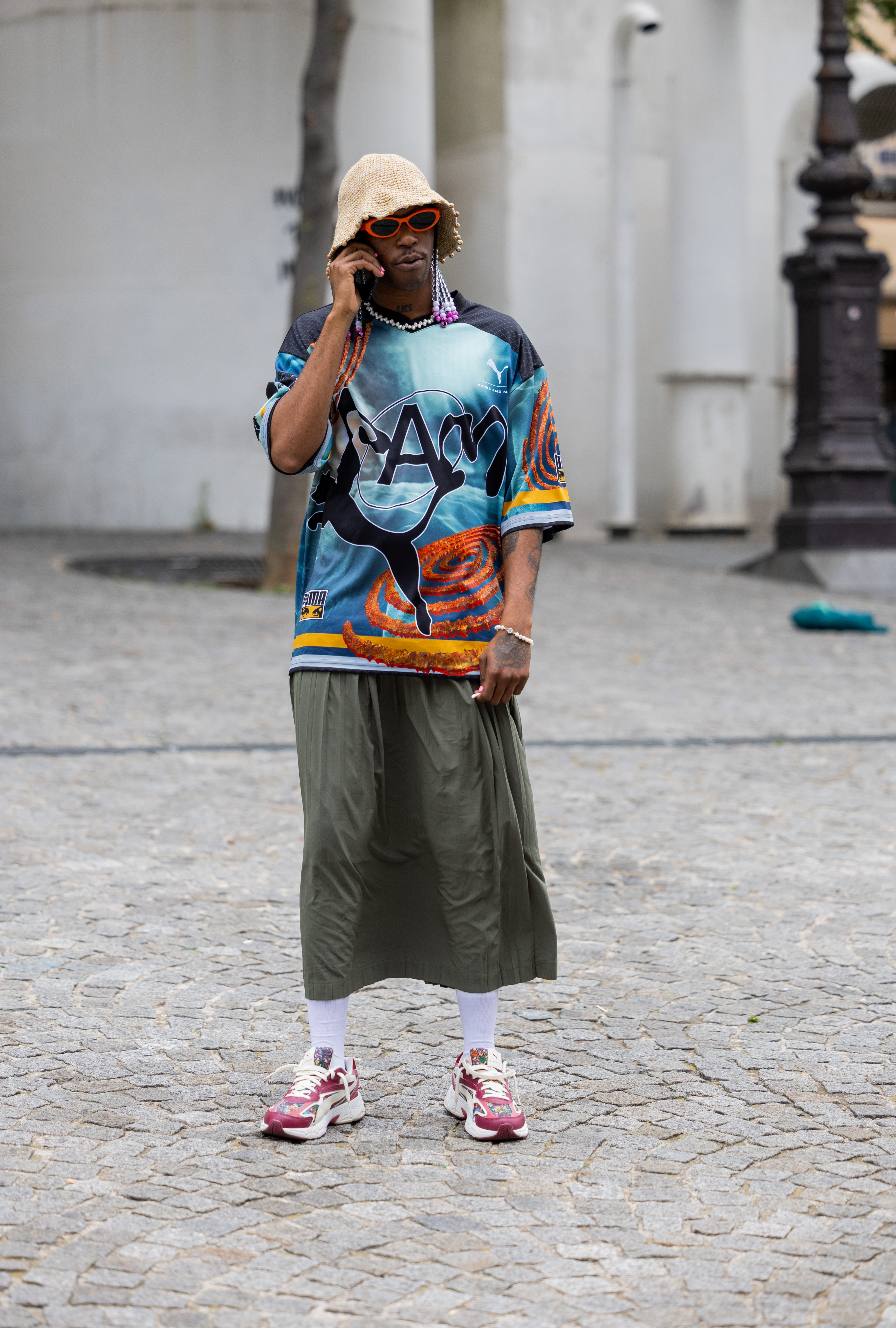 Street Style – Paris Fashion Week – Menswear Spring/Summer 2024 : Day One Look no street style da semana de moda masculina de primavera-verão 2024 em Paris. Homem usando camiseta estampada, saia midi e meia branca com tênis esportivo