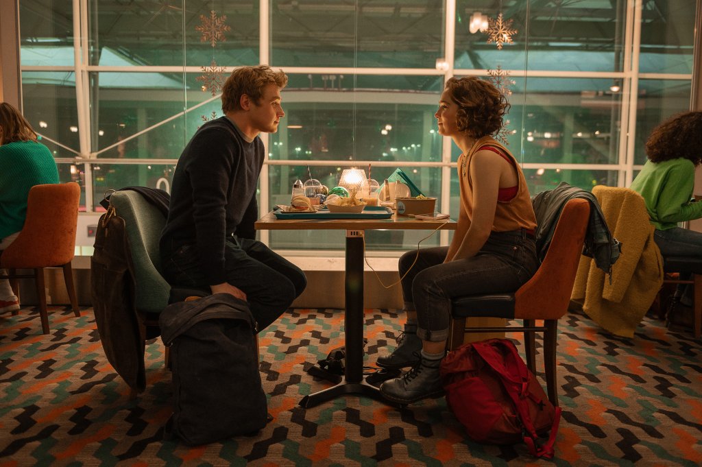 Haley Lu Richardson como Hadley Sullivan e Ben Hardy como Oliver Jones em cena de Amor à Primeira Vista; eles estão sentados em um restaurante de frente um para o outro enquanto se olham