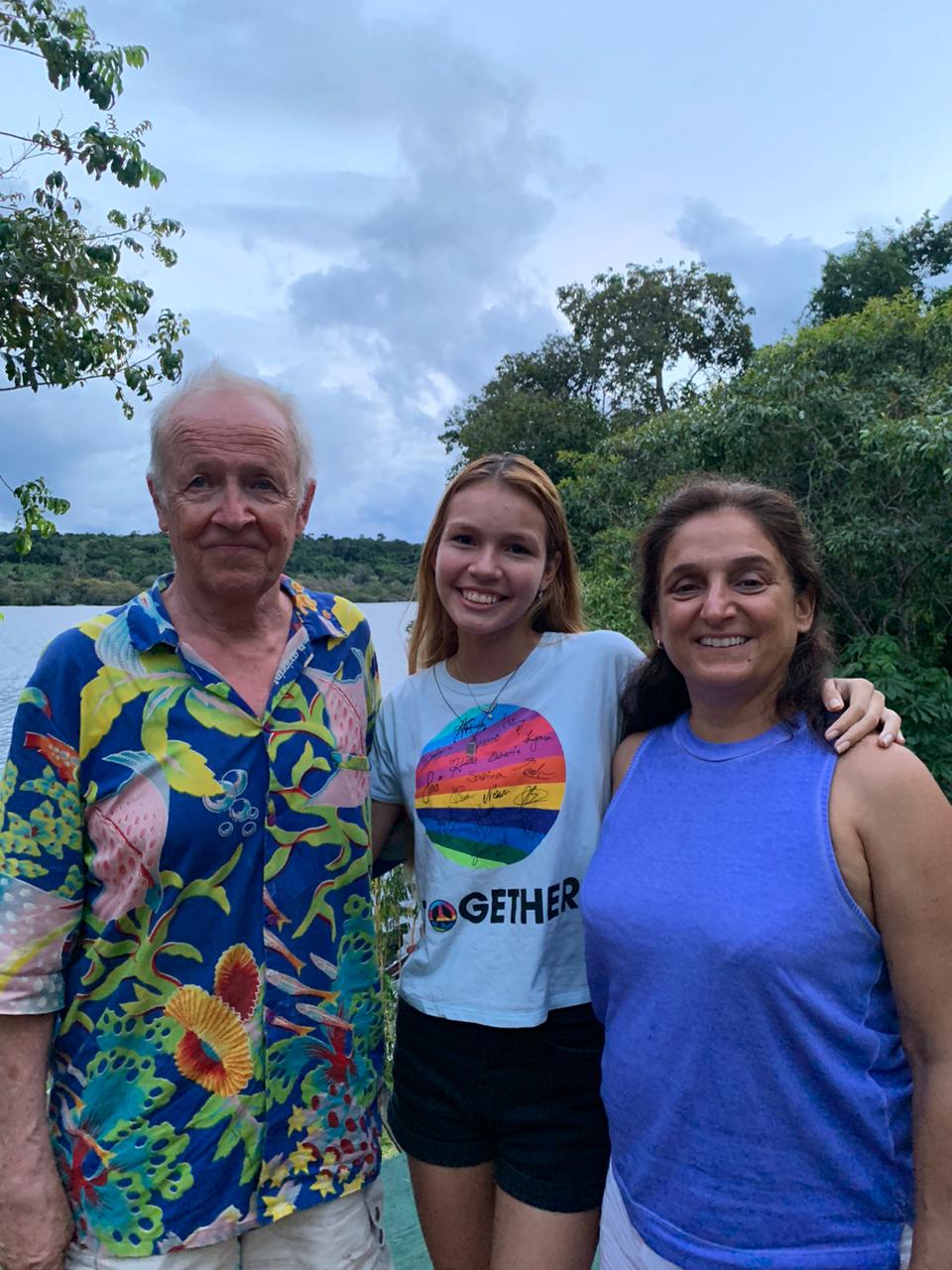 zahyra-diretores-trupes Doi lado esquerdo um senhor está vestindo uma camisa colorida, no meio uma garota loira de camiseta branca e do lado direito uma mulher de cabelos morenos e de camiseta azul