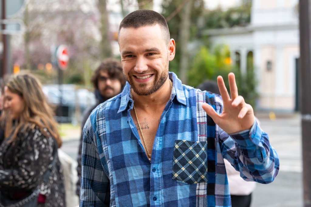 Liam Payne sorrindo para foto enquanto acena com uma das mãos