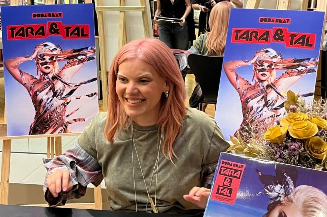 duda beat Duda Beat sorrindo entre cópias do disco Tara e Tal em sessão de autógrafos