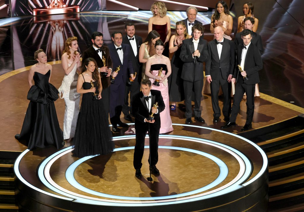 Elenco e equipe de Anora no palco do Oscar 2025 recebendo o prêmio de Melhor Filme.