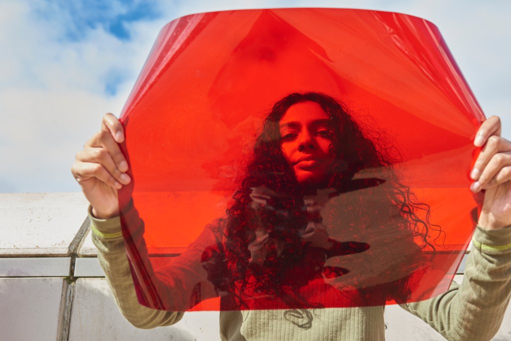 Jovem mulher segurando um filtro vermelho na frente do rosto