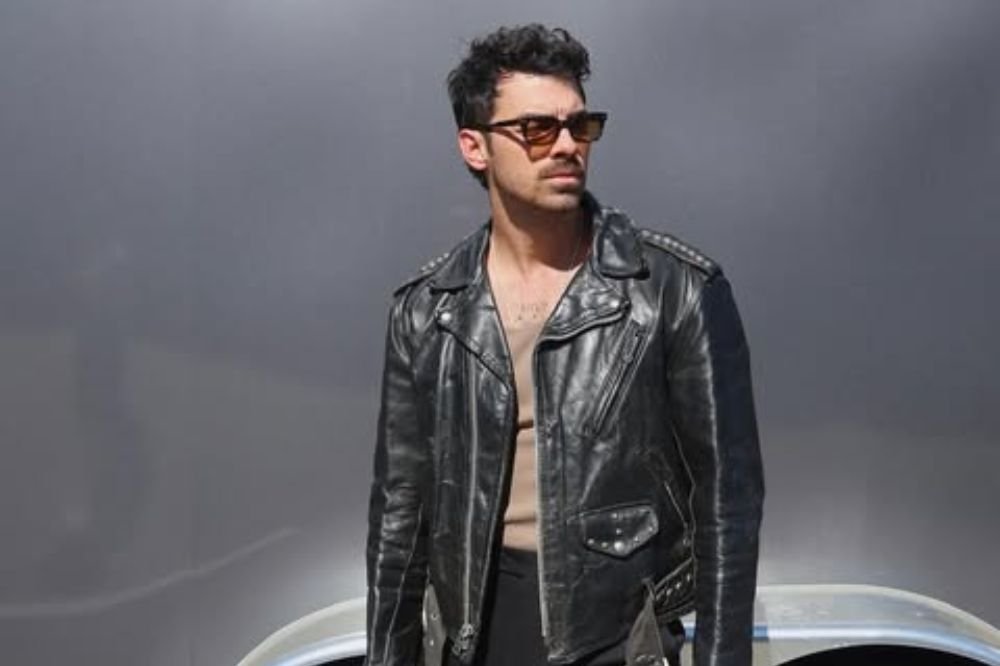 Joe Jonas posando para foto olhando para o lado e usando óculos de sol