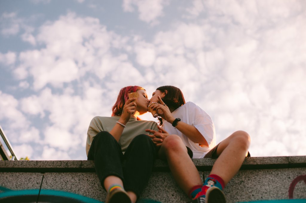 Duas garotas sentadas se beijando enquanto tomam sorvete