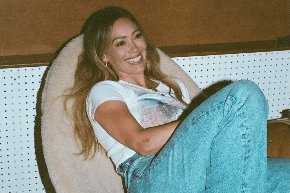 Hillary Duff sorri deitada numa poltrona