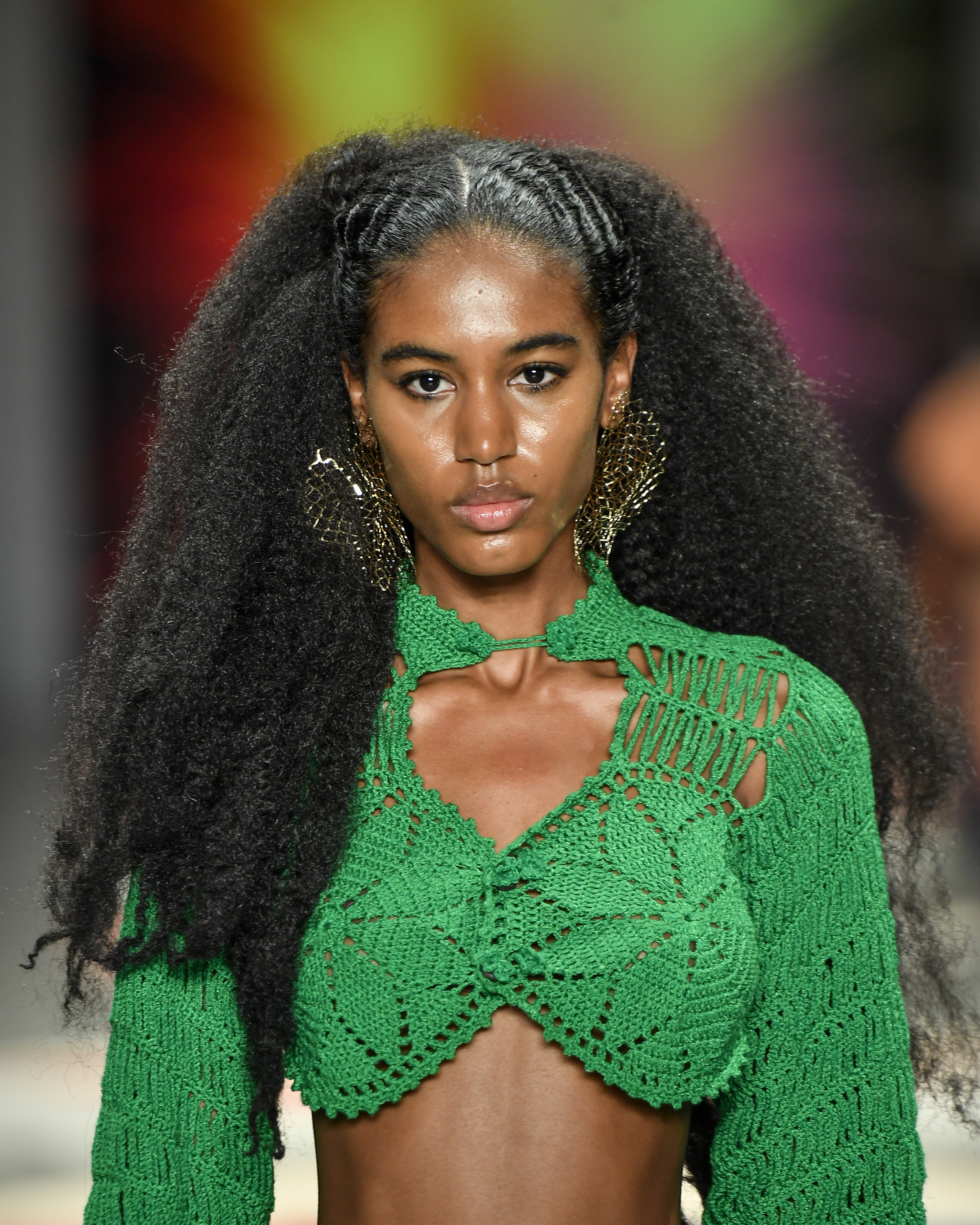 Modelo desfilando para a marca Ateliê Mão de Mãe com sobrancelha descolorida e batom vermelho